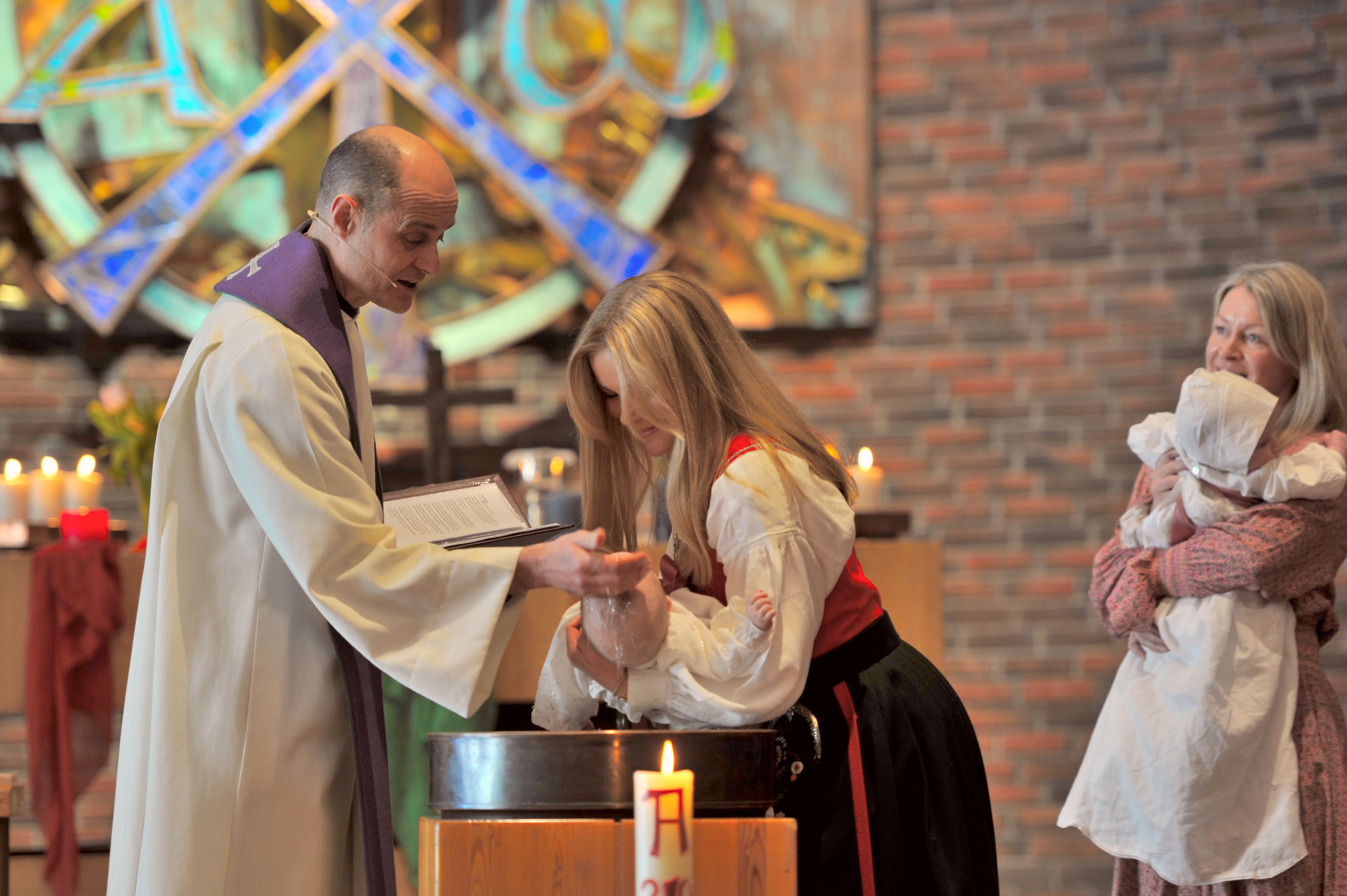 En prest som døper et spedbarn i Østerås kirke